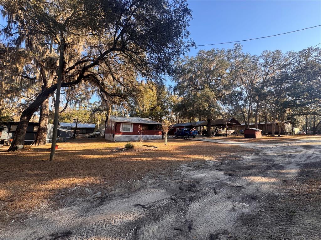 A red mobile home sits on a dirt lot shaded by large, moss-covered oak trees — 0 198TH LANE, FORT MC COY, FL