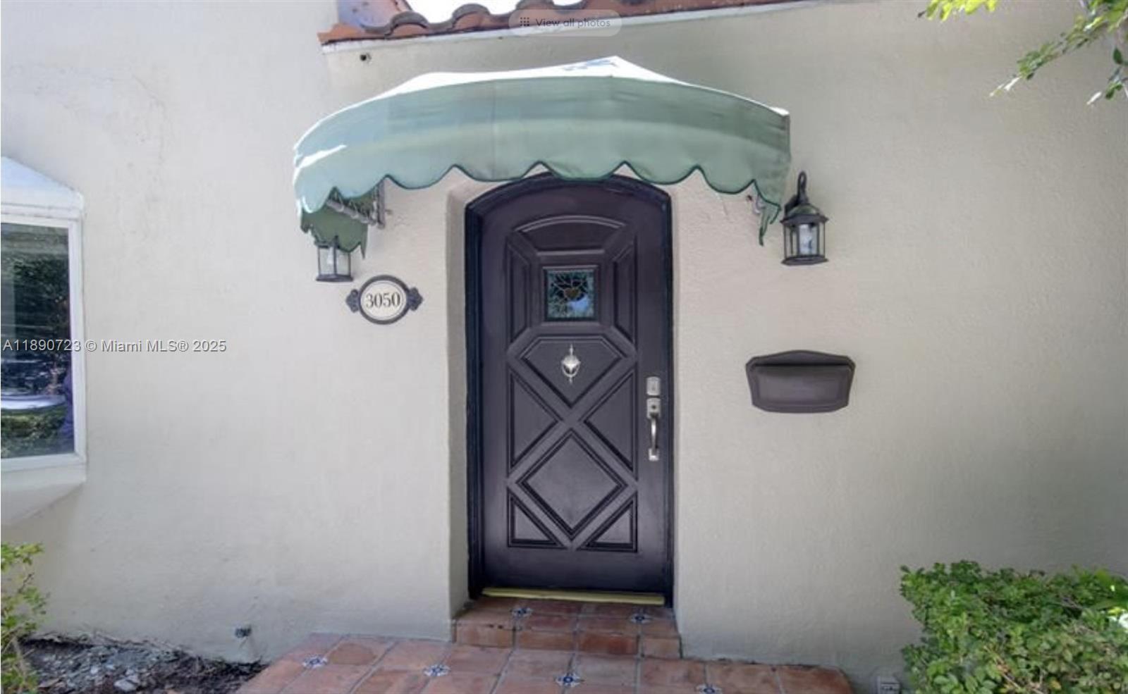 The exterior entrance features a dark arched door, a green awning, and a tiled porch — 3050 Alton Rd, Miami Beach FL 33140, MIAMI BEACH, FL