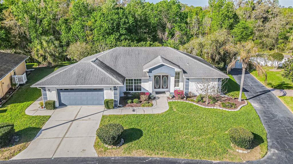 An aerial view of a single-story house with a gray roof, garage, and front lawn — 10504 MOSHIE LANE, SAN ANTONIO, FL
