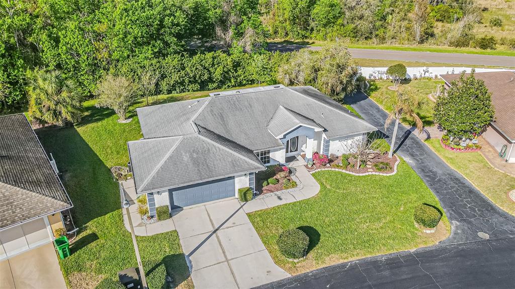 An aerial view shows a single-story house with a gray roof, garage, and landscaped yard — 10504 MOSHIE LANE, SAN ANTONIO, FL