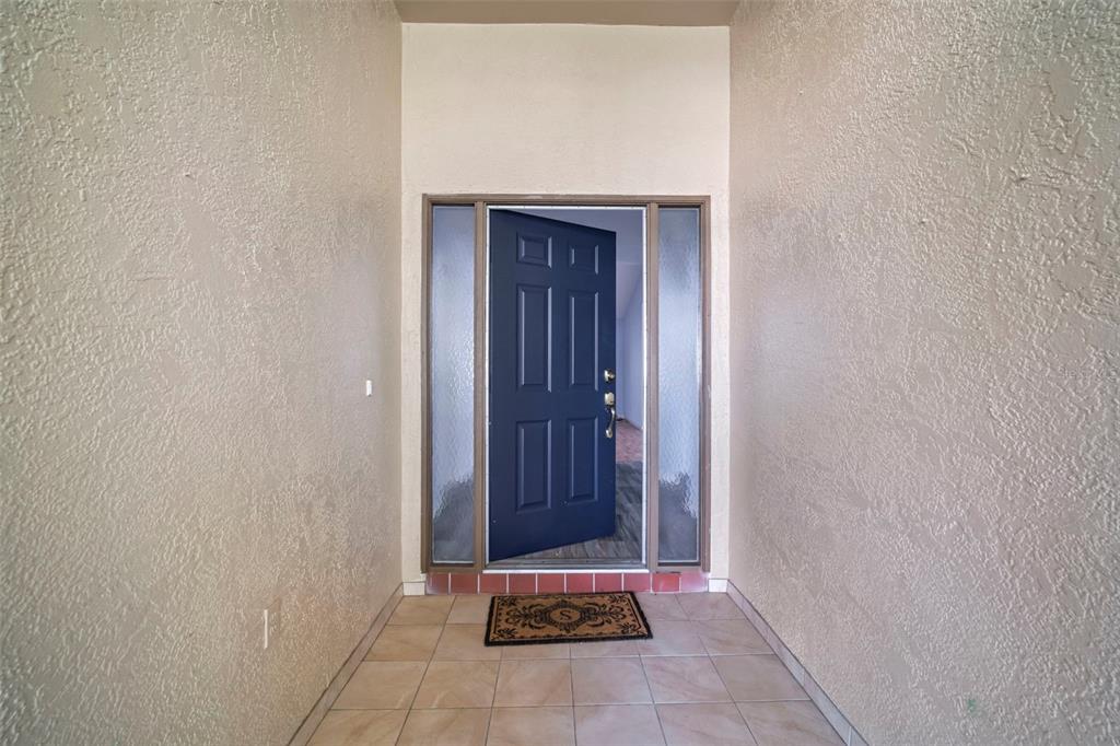 A front entryway features a blue door with glass sidelights and tiled flooring — 1609 LAUGHTON PLACE, SUN CITY CENTER, FL