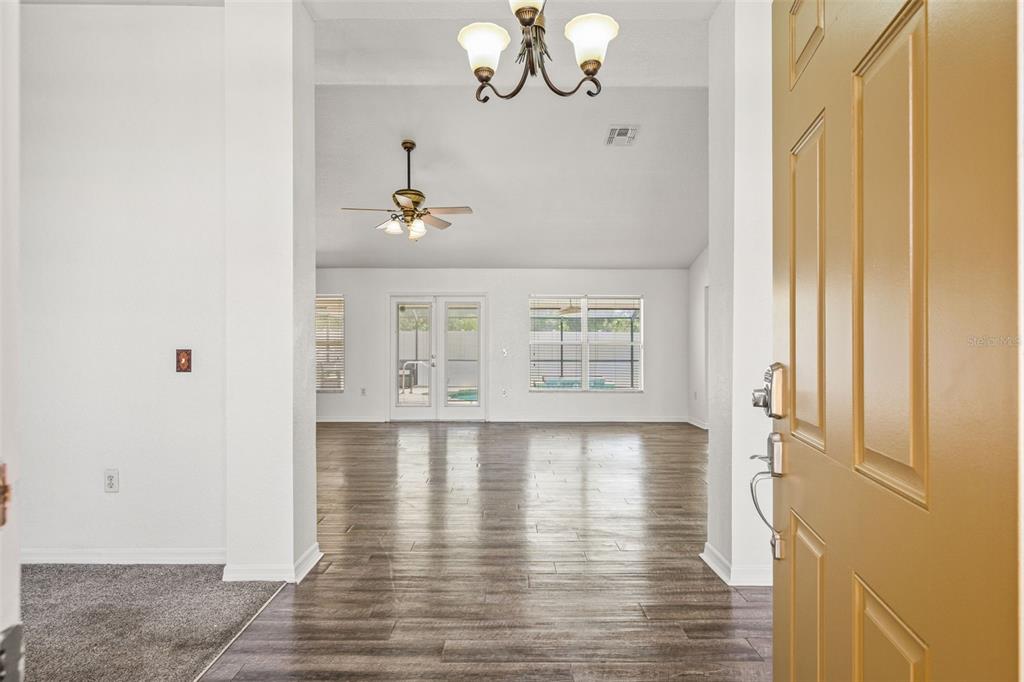An entryway opens into a living area with wood-look flooring, a ceiling fan, and windows — 14188 DORADO STREET, SPRING HILL, FL
