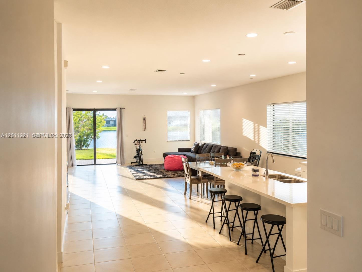 An open-concept living area features a kitchen island, dining table, sofa, and sliding glass doors — 4993 OFANTO LN, Ave Maria FL 34142, AVE MARIA, FL