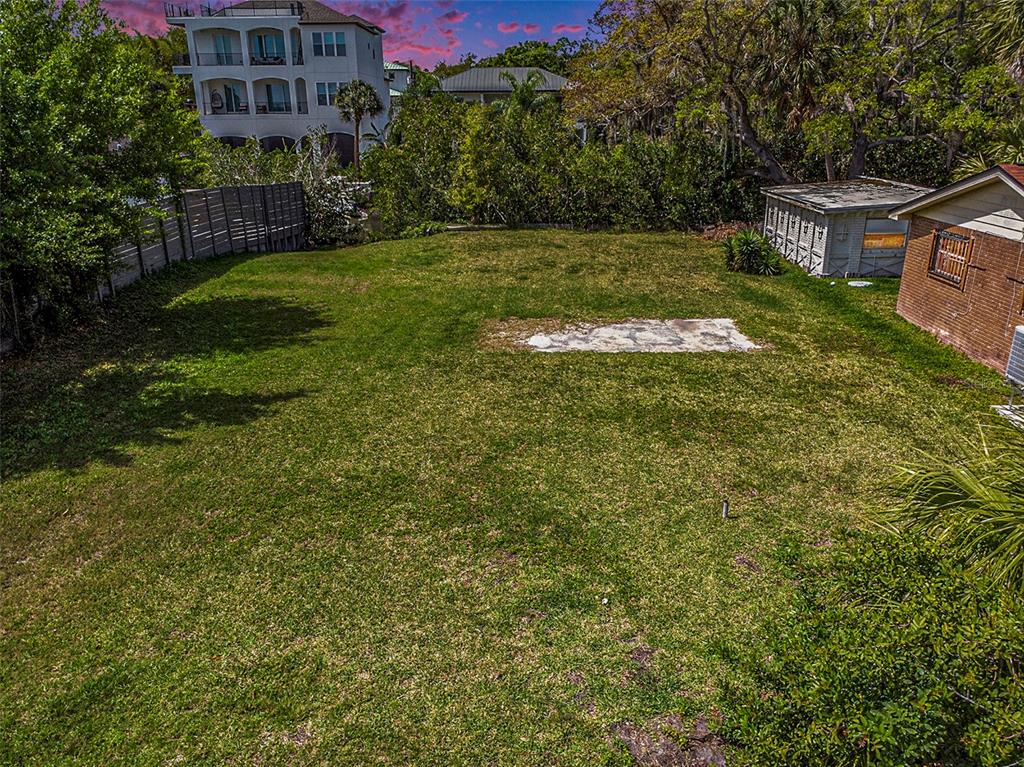 A grassy backyard features a concrete pad, a small shed, and a wooden fence — 7406 BAY DRIVE, TAMPA, FL