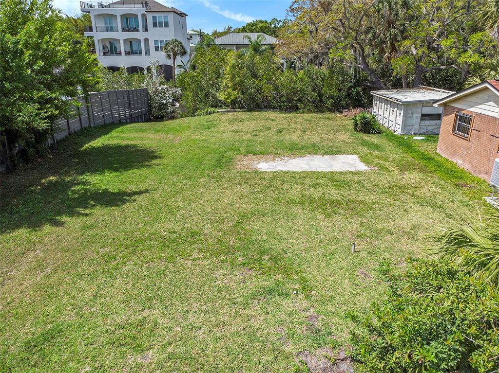 An elevated view of a grassy backyard featuring a concrete pad and a small shed — 7406 BAY DRIVE, TAMPA, FL