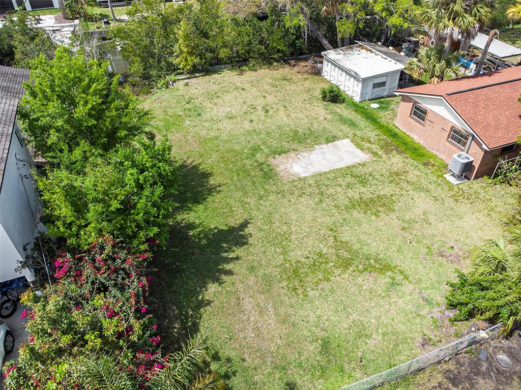 An aerial view shows a grassy backyard with a concrete pad and a small shed — 7406 BAY DRIVE, TAMPA, FL