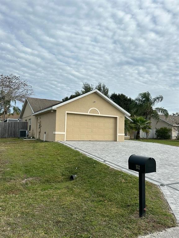 A tan, single-story house with a two-car garage and a paved driveway — 152 WHITEHALL STREET, DAVENPORT, FL