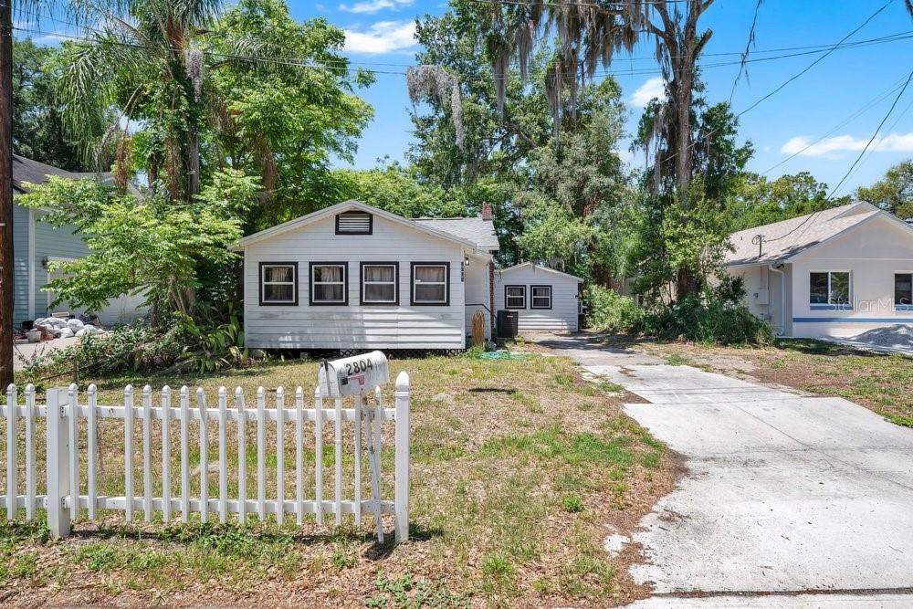 An aerial view shows a single-story house with a driveway surrounded by trees and buildings — 2804 KEYSTONE DRIVE, ORLANDO, FL