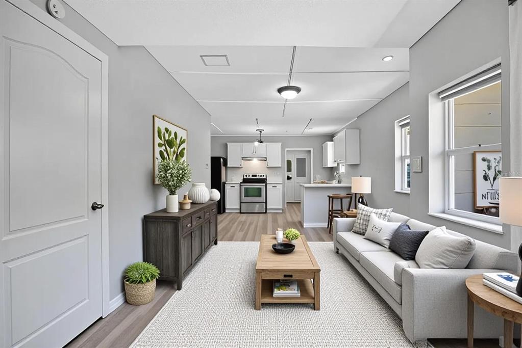A living room with light gray walls, a gray sofa, and an open-concept kitchen beyond — 2804 KEYSTONE DRIVE, ORLANDO, FL