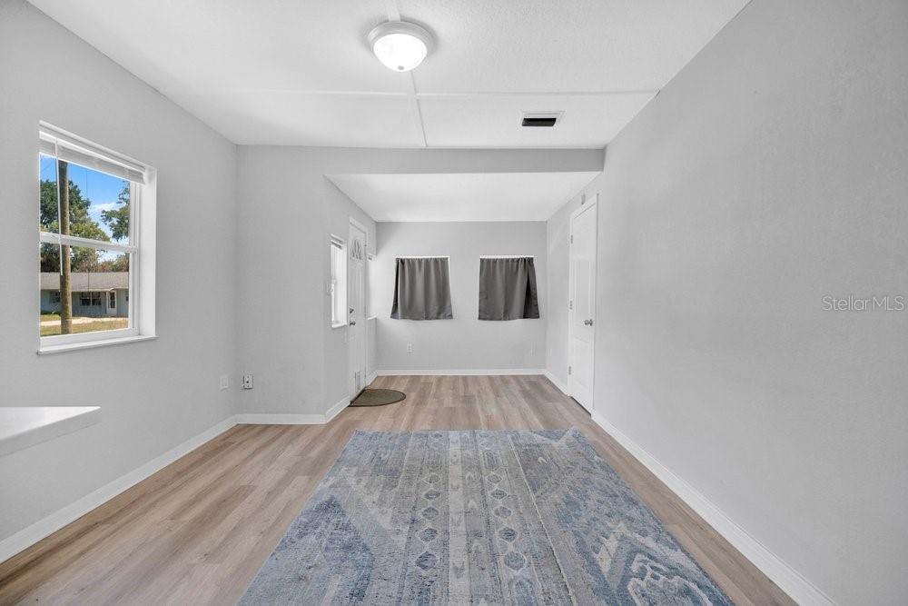 A bright room with light gray walls, wood-look flooring, a large rug, and two windows — 2804 KEYSTONE DRIVE, ORLANDO, FL