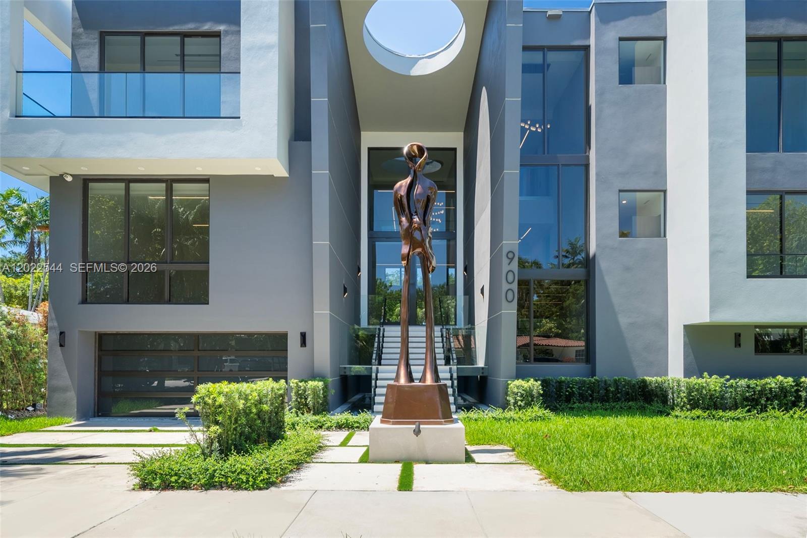 A modern multi-story home features a prominent bronze sculpture in front of the glass entrance — 900 NE 75th St, Miami FL 33138, MIAMI, FL