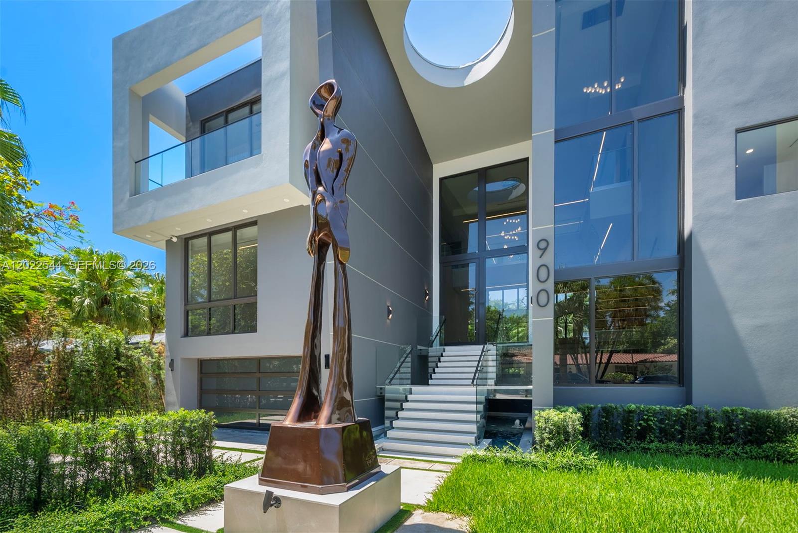 A modern multi-story home features a tall bronze sculpture in front of the glass entrance — 900 NE 75th St, Miami FL 33138, MIAMI, FL
