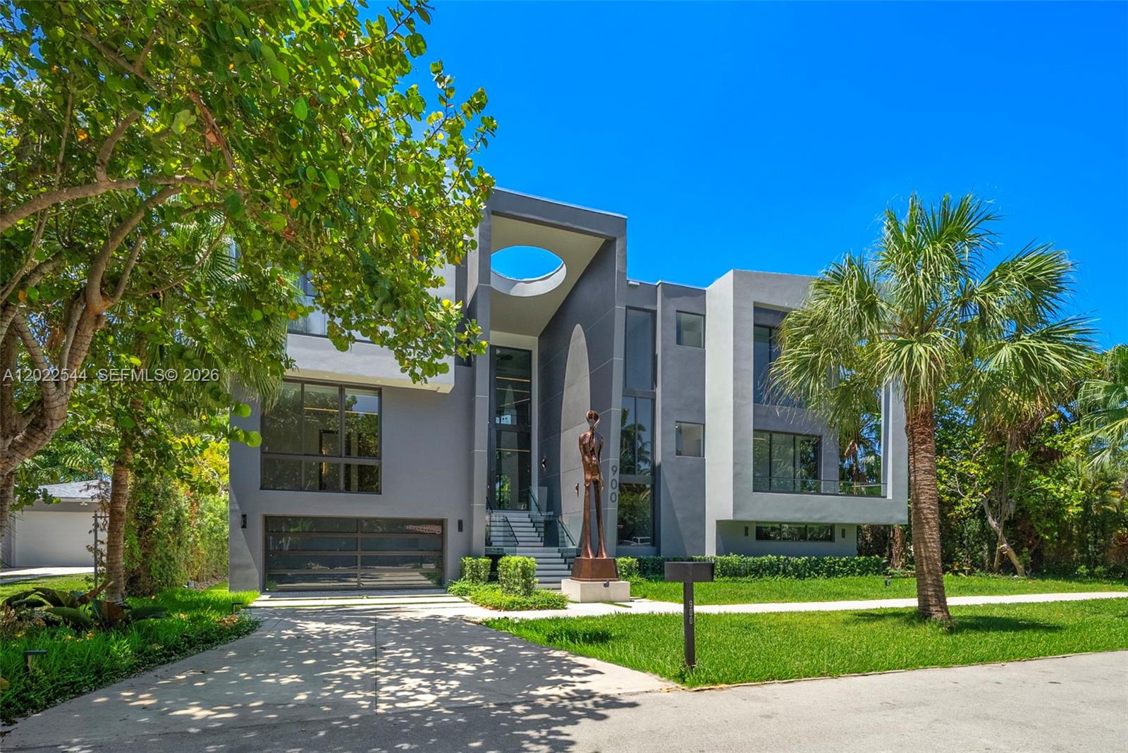 A modern three-story gray house features a circular cutout in the roof and a sculpture — 900 NE 75th St, Miami FL 33138, MIAMI, FL