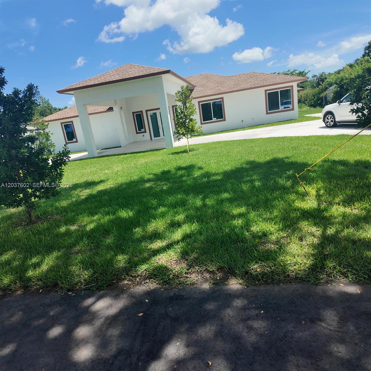 A white, single-story house with a brown roof and a covered front entryway — HOMESTEAD, FL