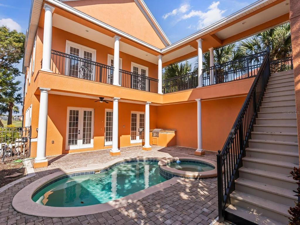 A two-story orange house features a pool, spa, and an outdoor staircase to a balcony — 1554 COROLLA COURT, REUNION, FL