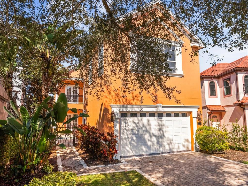 An orange two-story house with a white garage door and a brick paver driveway — 1554 COROLLA COURT, REUNION, FL