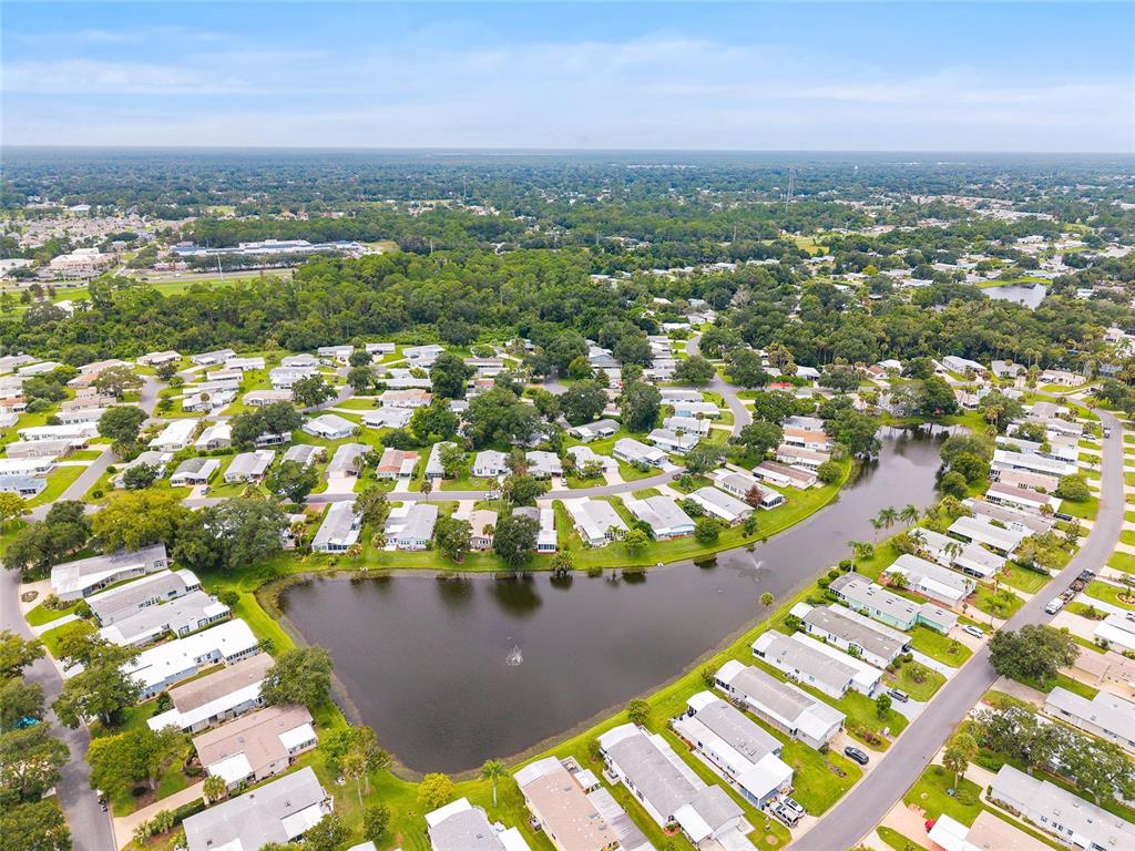 An aerial view shows a residential community with many houses surrounding a central pond — 621 STARBOARD AVENUE, EDGEWATER, FL