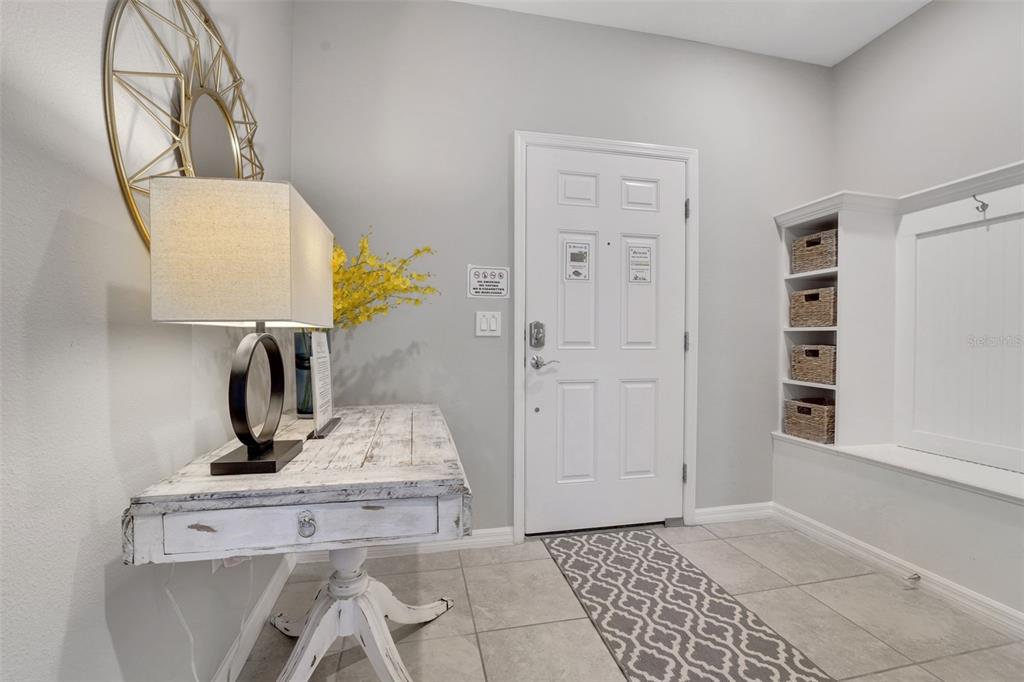 An entryway features a white console table, a lamp, a bench with cubbies, and tile flooring — 720 GARDENIA LANE, DAVENPORT, FL