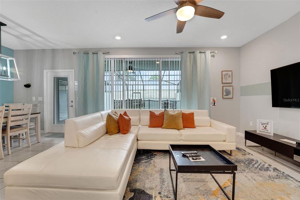 A living room features a white sectional sofa, a coffee table, and a sliding glass door — 720 GARDENIA LANE, DAVENPORT, FL