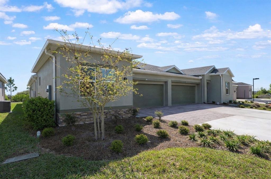 A side view of a single-story house with a two-car garage and landscaped front yard — 3335 NW 52ND AVENUE ROAD, OCALA, FL