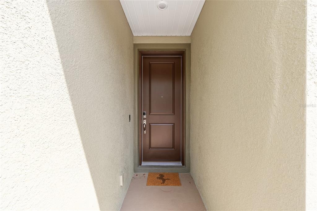 A brown front door is centered in a narrow, covered entryway with beige stucco walls — 3335 NW 52ND AVENUE ROAD, OCALA, FL