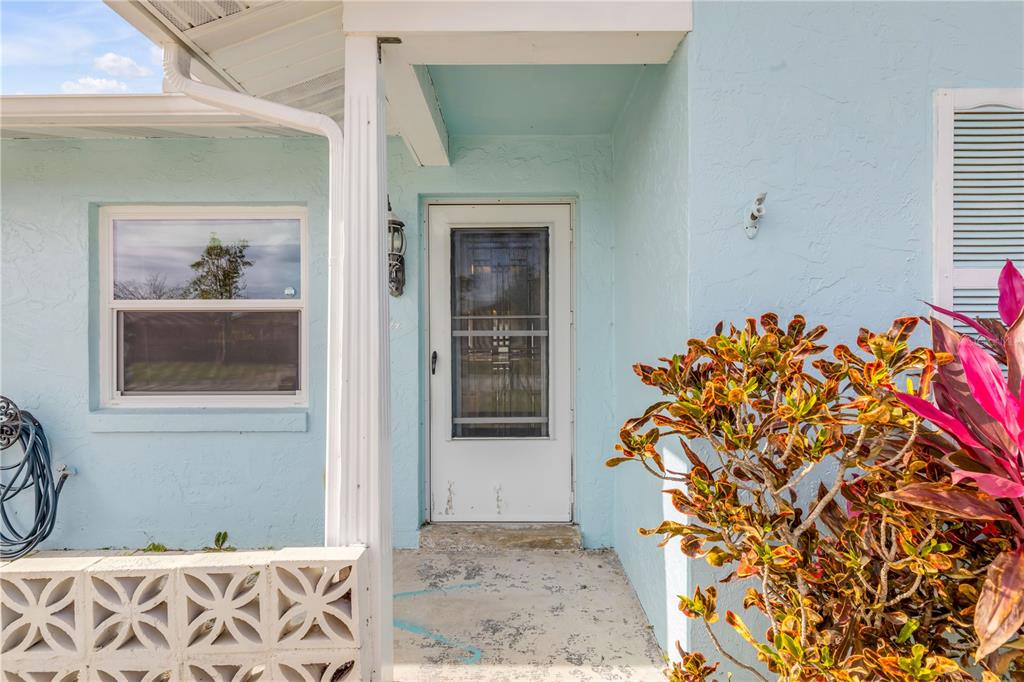 The exterior of a light blue house features a white front door and decorative concrete blocks — 26 LAUGHING GULL LANE, EDGEWATER, FL