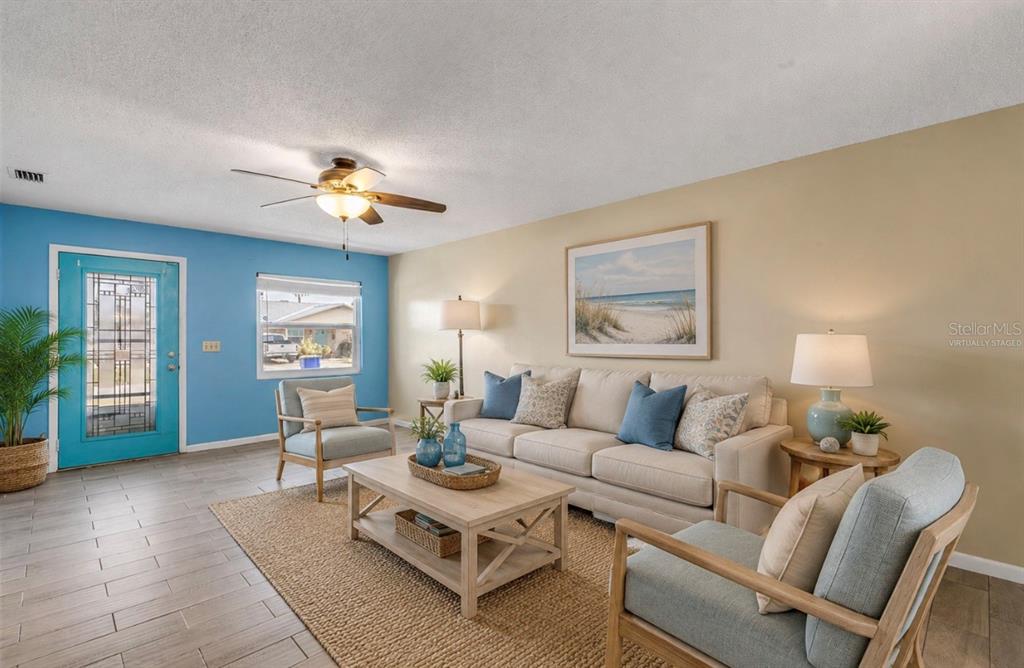 A living room features a blue accent wall, a beige sofa, and two armchairs — 26 LAUGHING GULL LANE, EDGEWATER, FL
