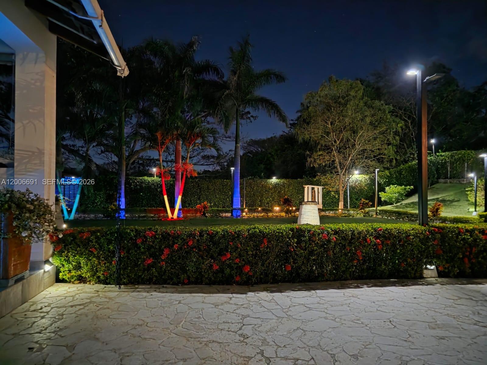 A night view of a landscaped backyard with illuminated palm trees and a stone patio — Finca Villa Guadalupe Finca #175, FL 000000, FL