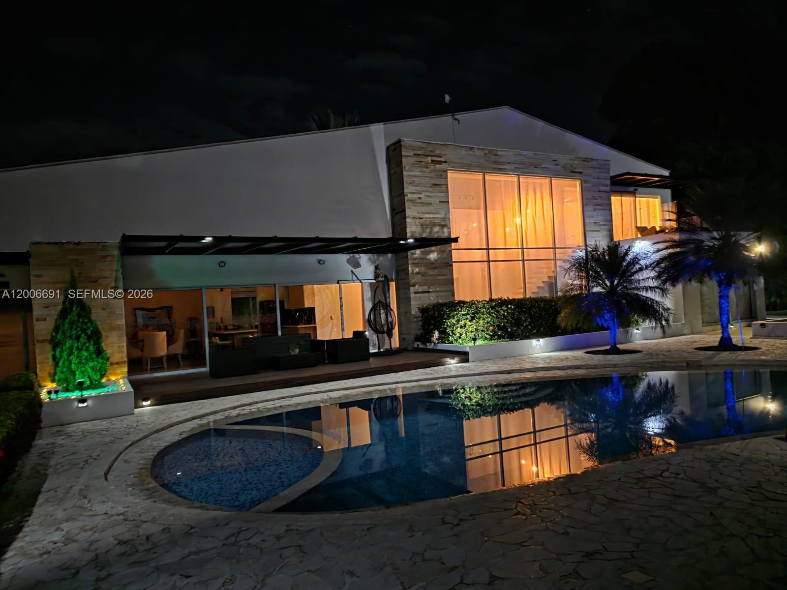 A modern house exterior at night features a swimming pool, stone patio, and large windows — Finca Villa Guadalupe Finca #175, FL 000000, FL