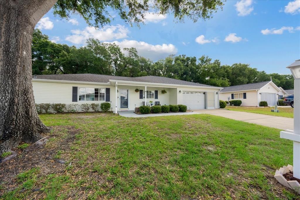 A single-story house with light siding, a front porch, and an attached garage — 14748 SW 112TH CIRCLE, DUNNELLON, FL
