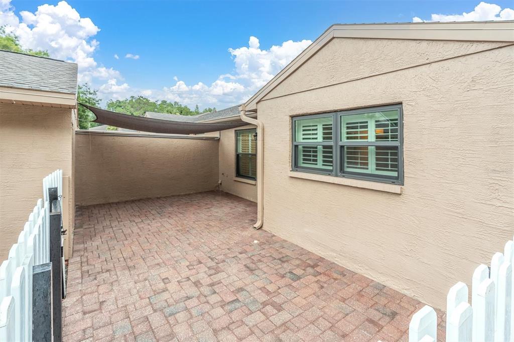 A paved patio area is enclosed by white picket fencing and the exterior house walls — 3203 CHARTER CLUB DRIVE UNIT B, TARPON SPRINGS, FL
