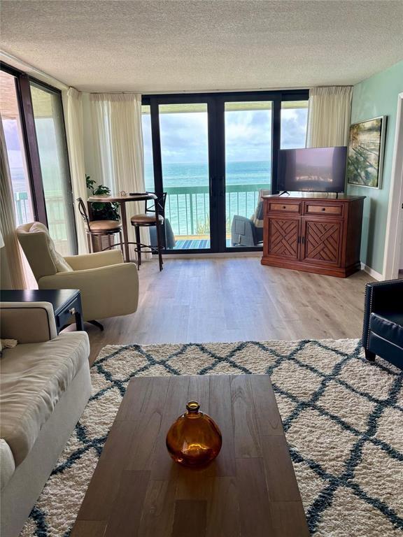 A living room features a wooden coffee table, a rug, and sliding doors overlooking the ocean — 9940 S Ocean Drive # 501, Jensen Beach FL 34957, JENSEN BEACH, FL