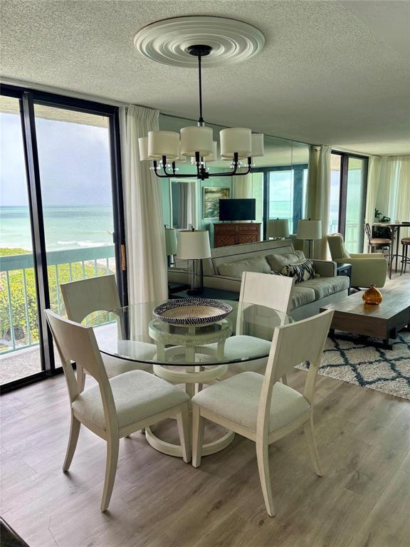 A dining area with a glass table and chairs sits before a living room with ocean views — 9940 S Ocean Drive # 501, Jensen Beach FL 34957, JENSEN BEACH, FL