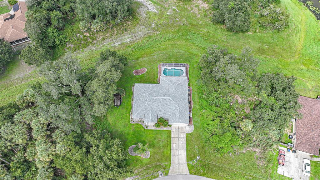 An aerial view shows a house with a pool and screened lanai surrounded by trees — 3565 NASHVILLE ROAD, NORTH PORT, FL