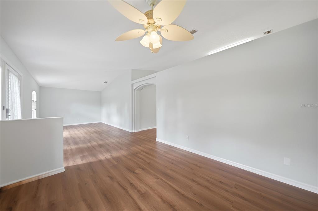 A spacious, empty room features light gray walls, wood-look flooring, and a ceiling fan — 3565 NASHVILLE ROAD, NORTH PORT, FL