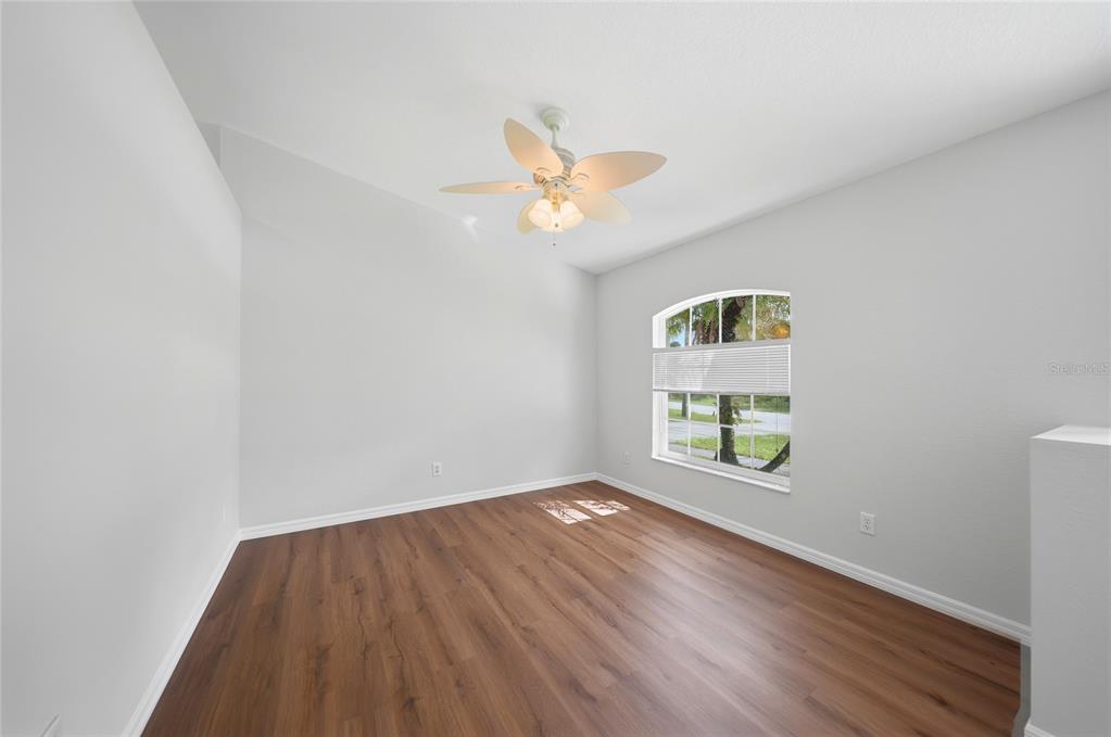 An empty room with light gray walls, wood-look flooring, a ceiling fan, and an arched window — 3565 NASHVILLE ROAD, NORTH PORT, FL