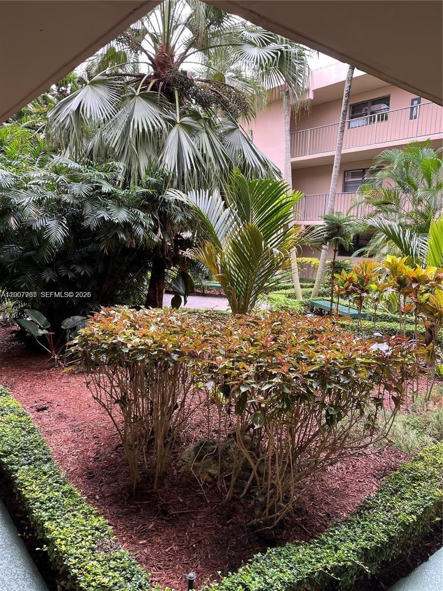 A view of a landscaped courtyard with tropical plants and a multi-story building exterior — 10525 SW 112th Ave # 114, Miami FL 33176, MIAMI, FL