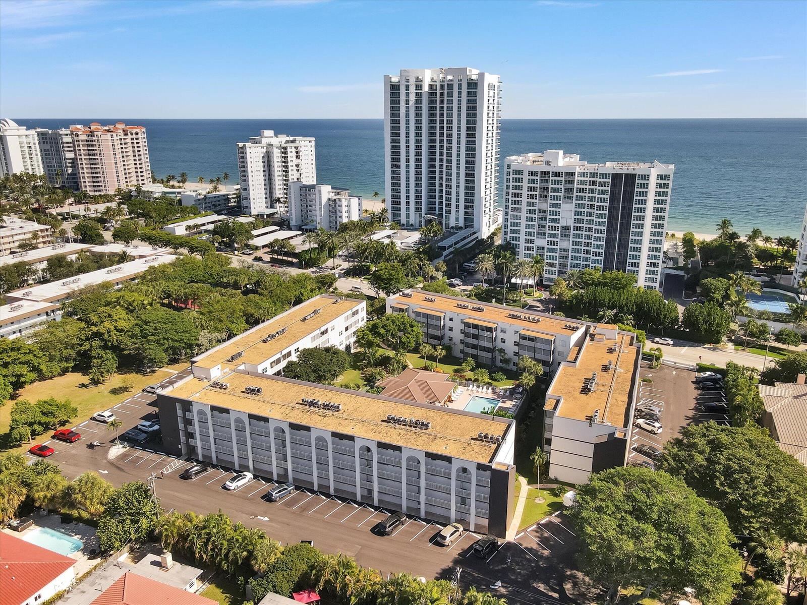 An aerial view shows a multi-story apartment complex with a central pool and oceanfront buildings — 1541 S Ocean Boulevard # 211, Pompano Beach FL 33062, POMPANO BEACH, FL