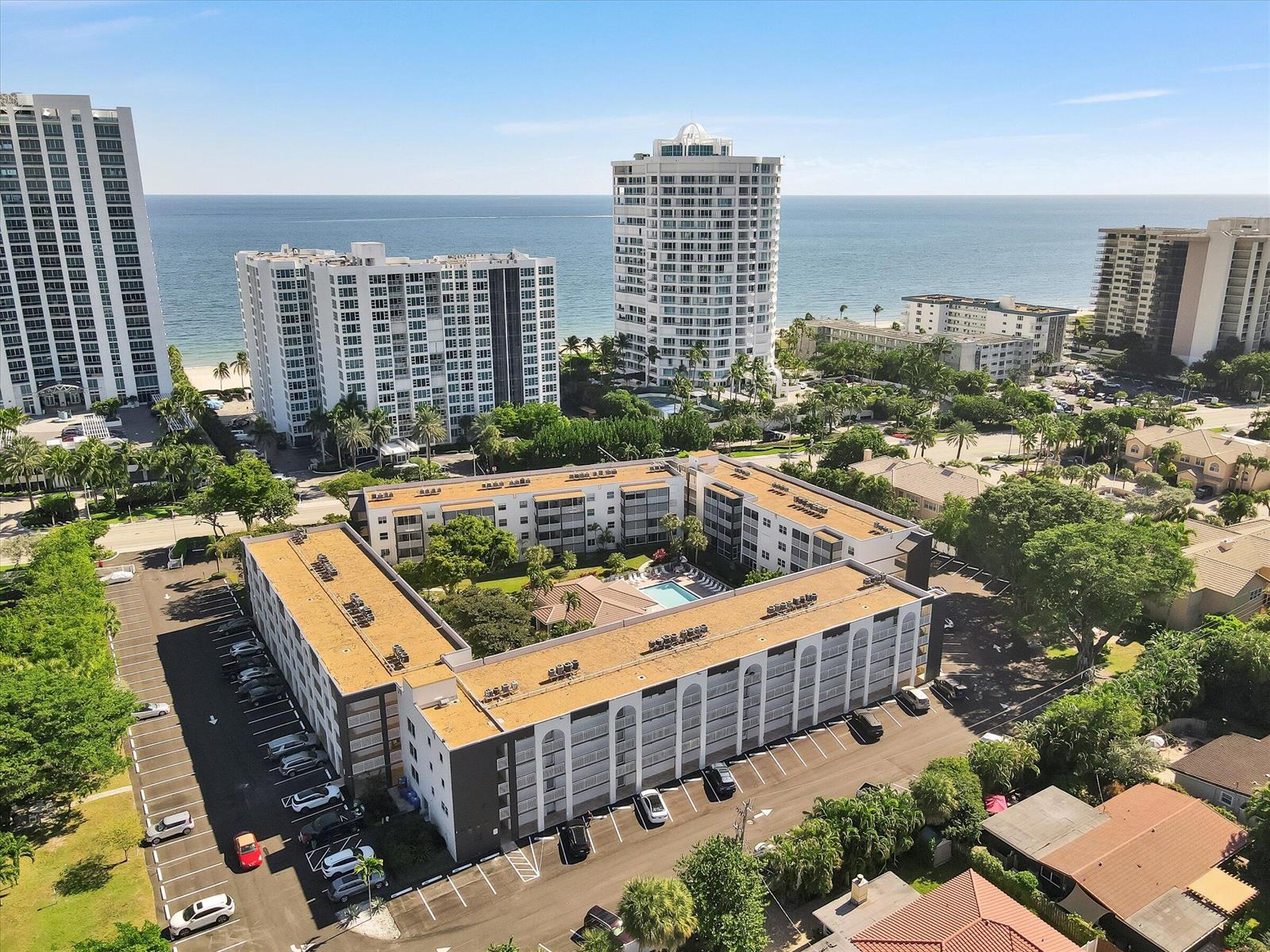 An aerial view shows a multi-story apartment complex with a central pool near the ocean — 1541 S Ocean Boulevard # 211, Pompano Beach FL 33062, POMPANO BEACH, FL