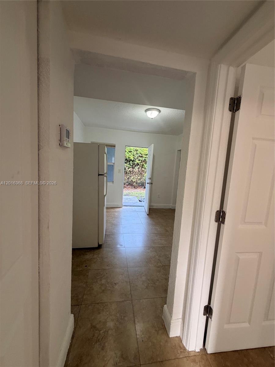A view through a doorway shows a kitchen with tile floors and an open door — 219 NW 10th St # 2, Miami FL 33136, MIAMI, FL