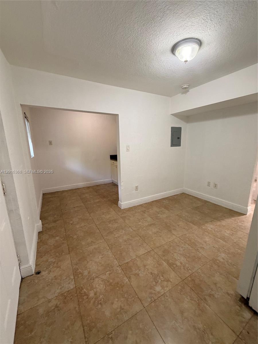 This room features light-colored walls, tan tile flooring, and an open doorway to a kitchen — 219 NW 10th St # 2, Miami FL 33136, MIAMI, FL