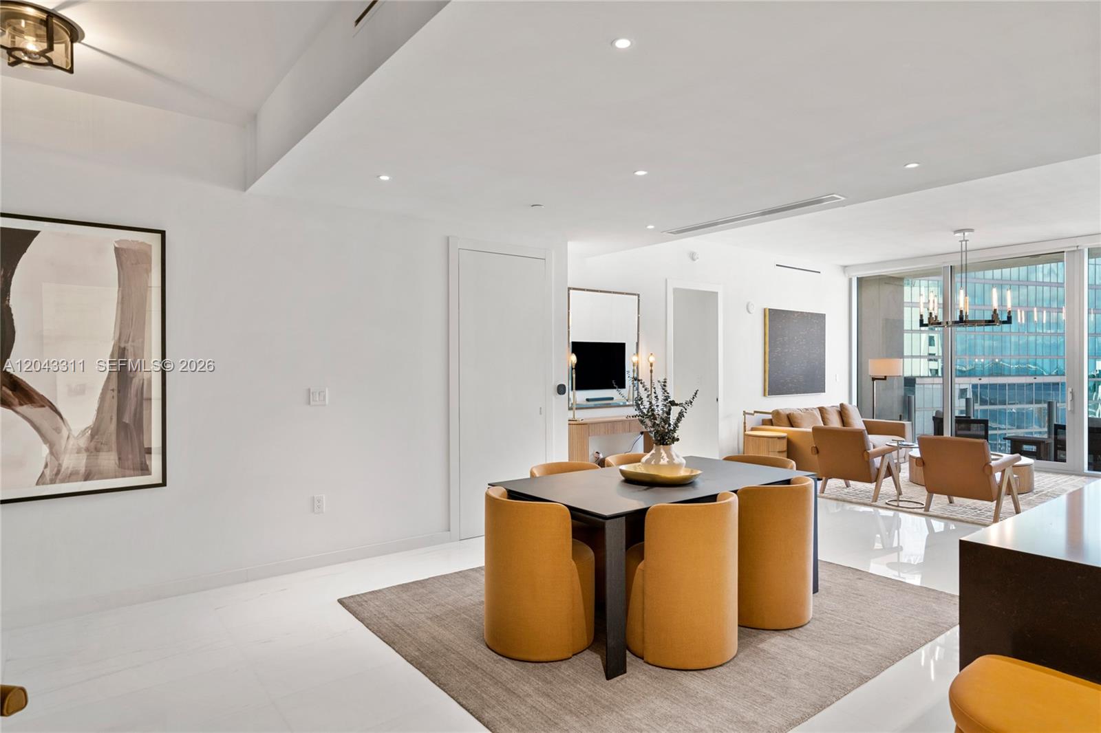 A dining area with yellow chairs and a dark table sits before a living room — 300 Biscayne Boulevard Way # 4009W, Miami FL 33131, MIAMI, FL