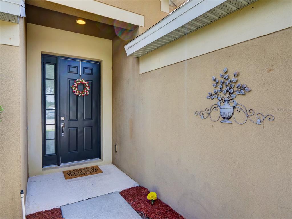 A dark front door with a wreath and a metal wall decoration on the porch — 2972 SANTA MARIA AVENUE, CLERMONT, FL