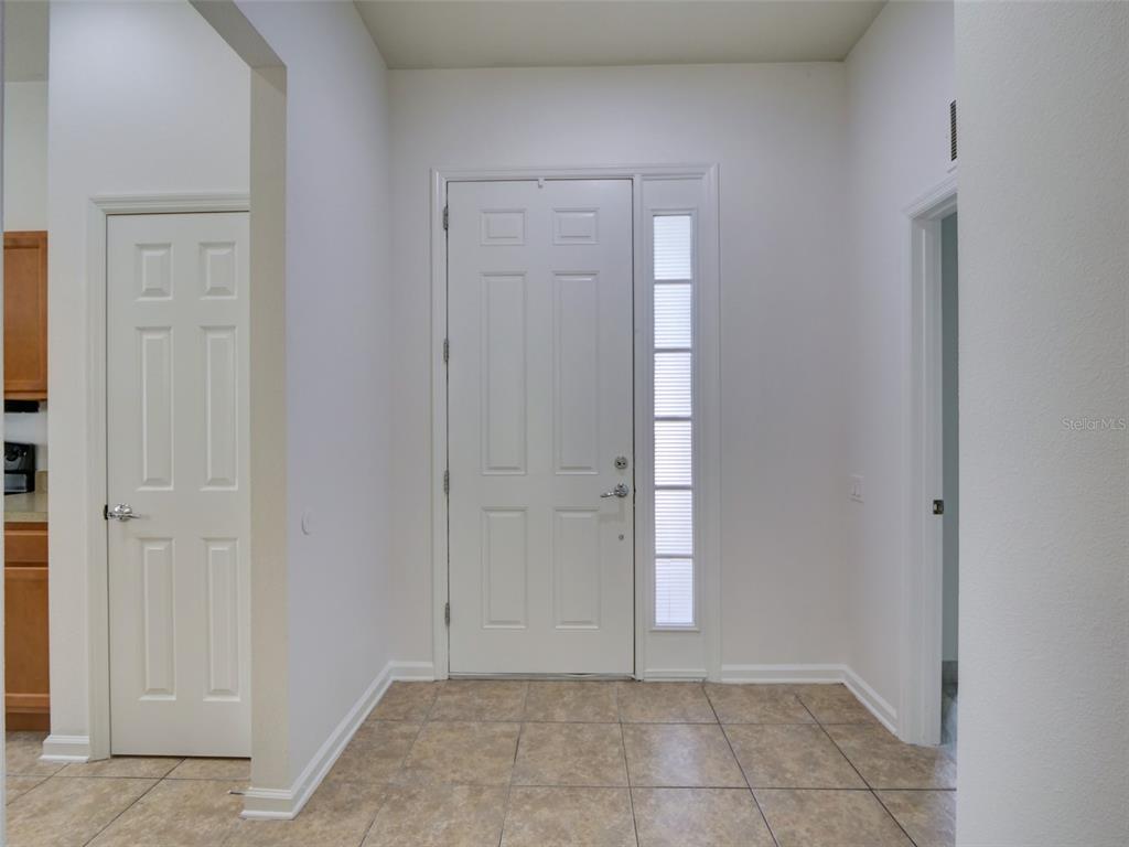 A white front door with a side window sits in a tiled entryway — 2972 SANTA MARIA AVENUE, CLERMONT, FL
