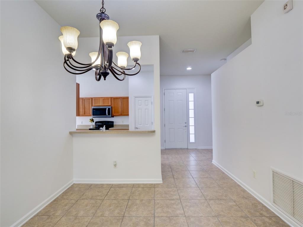 A dining area with a chandelier overlooks a kitchen with wood cabinets and tile flooring — 2972 SANTA MARIA AVENUE, CLERMONT, FL