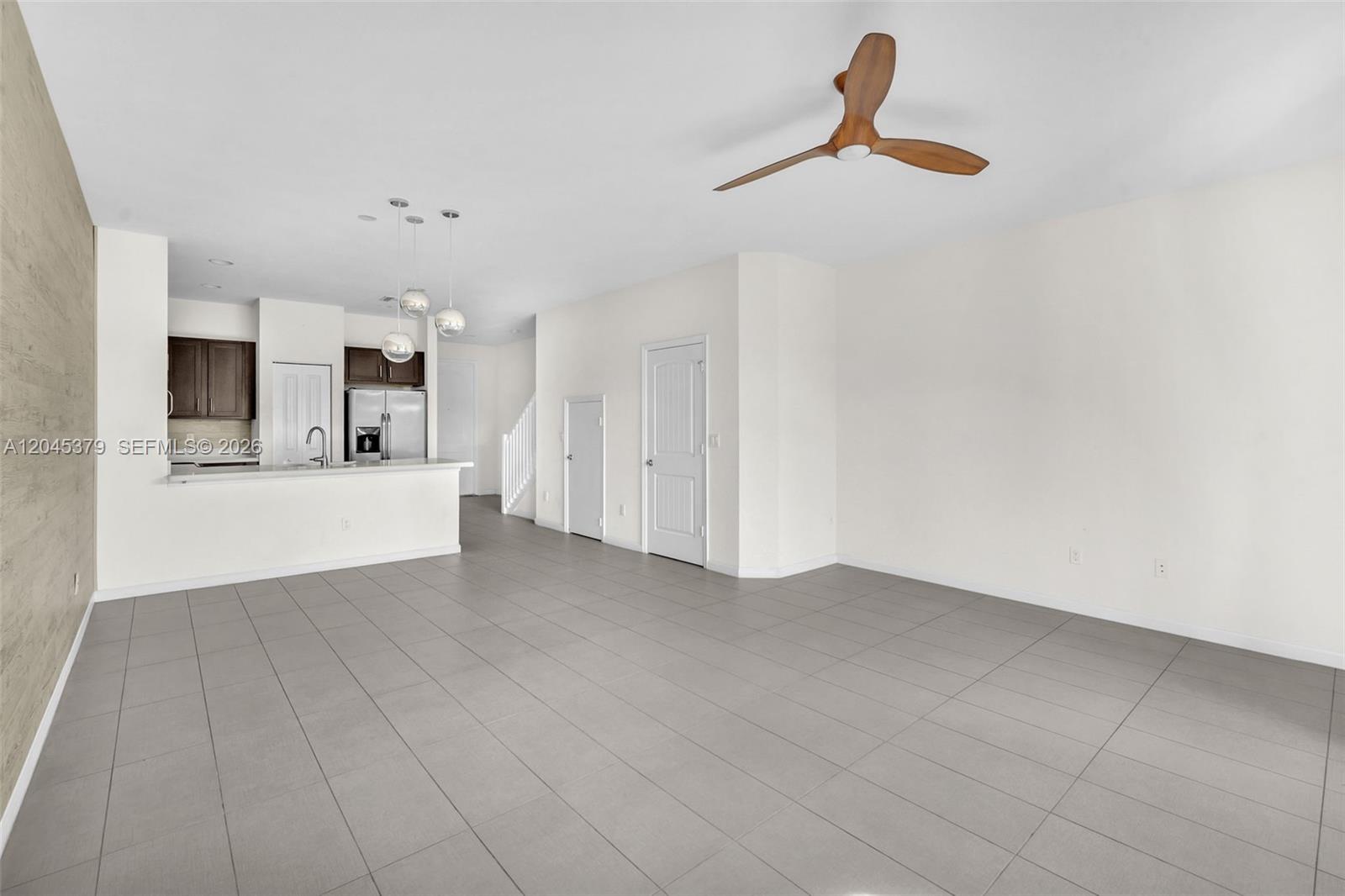 An open-concept living area features gray tile flooring, a kitchen with dark cabinets, and a ceiling fan — OAKLAND PARK, FL