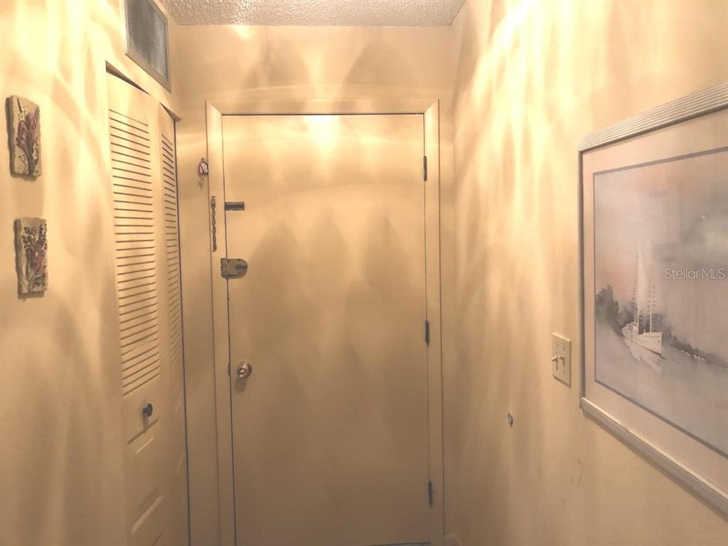 A narrow interior entryway features a white door, a louvered closet door, and wall art — 532 BAHIA CIRCLE UNIT A, OCALA, FL