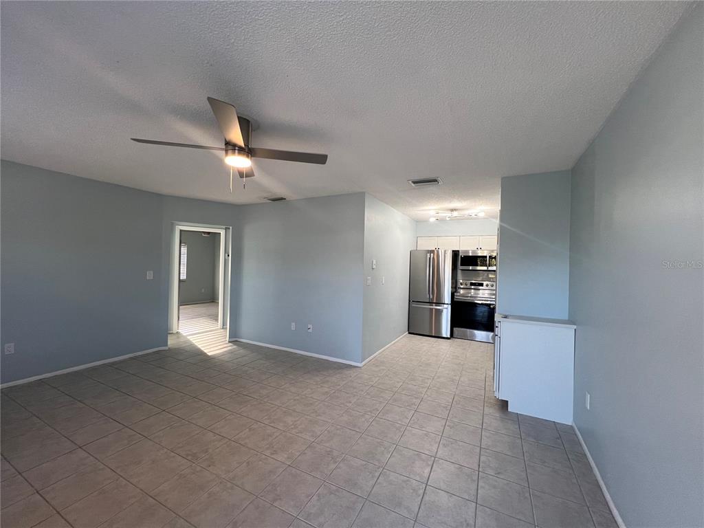 An open-concept living room and kitchen with light blue walls and tiled flooring — 810 KINGS COURT UNIT D, PUNTA GORDA, FL