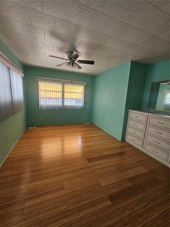 A bedroom with light green walls, wood flooring, a ceiling fan, and a white dresser — 18675 US HIGHWAY 19 N UNIT 498, CLEARWATER, FL