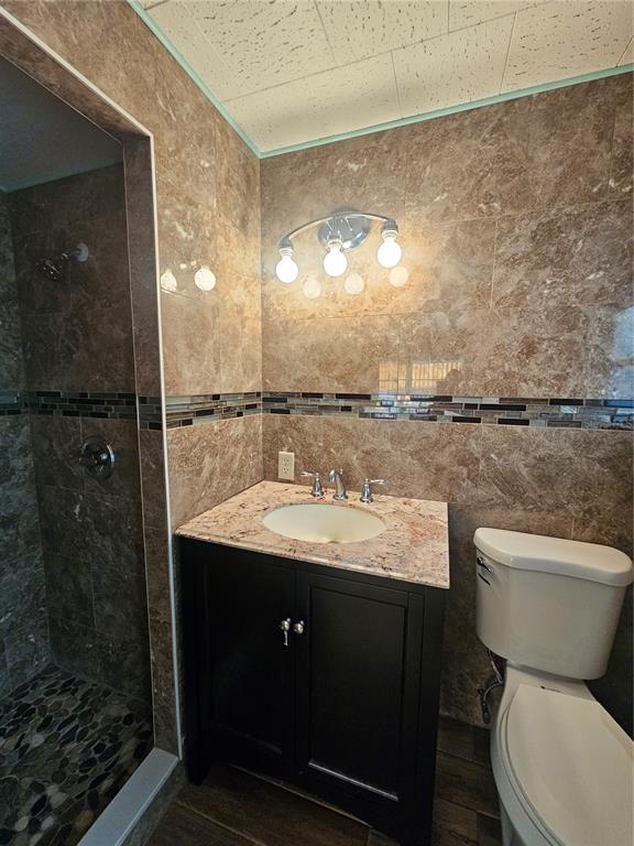 A bathroom features a dark vanity, granite countertop, tiled shower, and a toilet — 18675 US HIGHWAY 19 N UNIT 498, CLEARWATER, FL